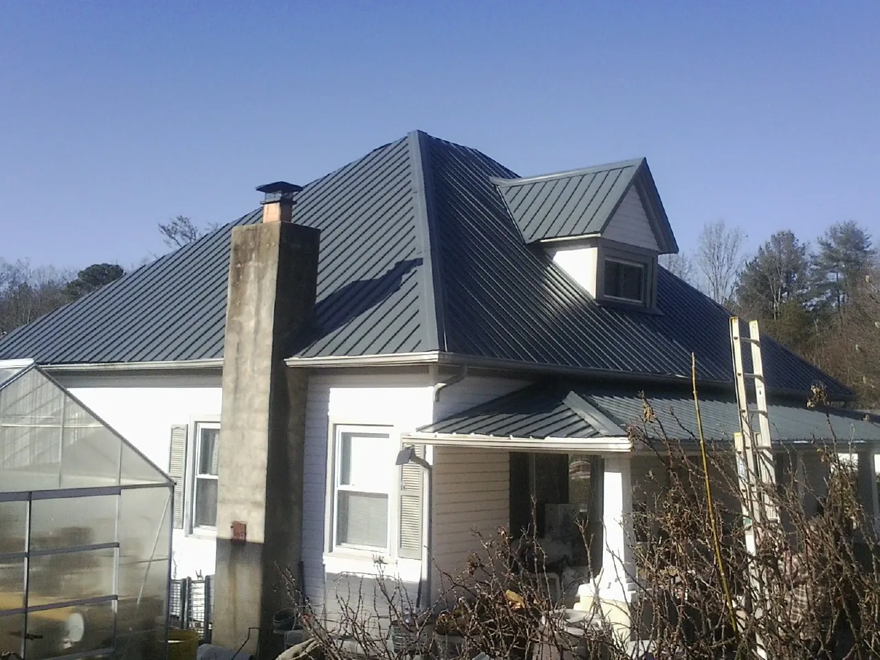 Dark blue standing seam metal roof on a white farmhouse with dormer — Slate & Tile Roof Repair by Roofing Brothers in Fox River Grove