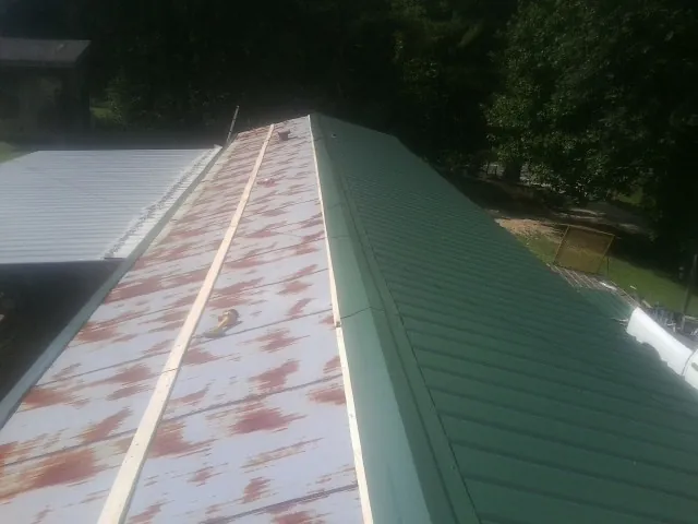 Old rusted panels beside newly installed green metal roofing — Wind Damage Roof Repair by Roofing Brothers in Fox River Grove