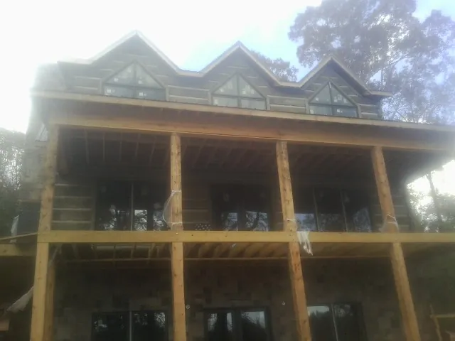 Dormers and porch framing on a large log home under construction — Roof Coating work by our crew in Fox River Grove