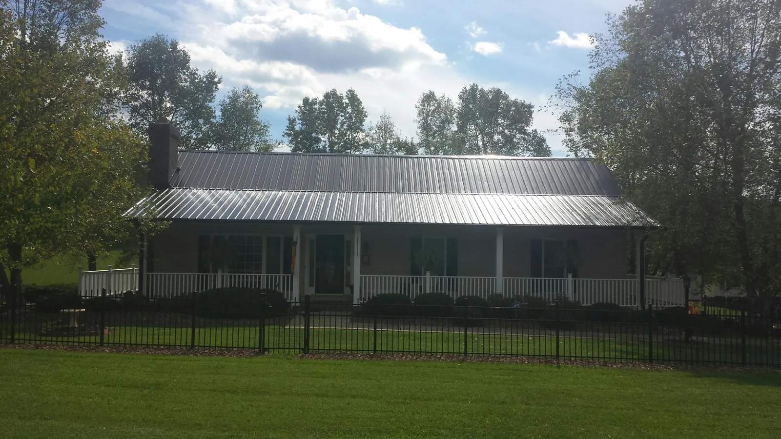 Gray metal roof on a brick ranch with a full width front porch — Gutter Guard Installation work by our crew in Fox River Grove