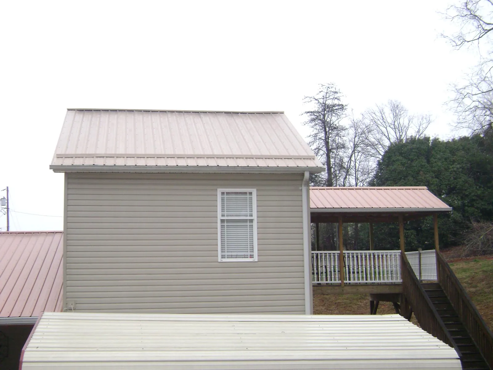 Tan metal roofs on a two story addition and attached porch, from a Roof Replacement job in Fox River Grove