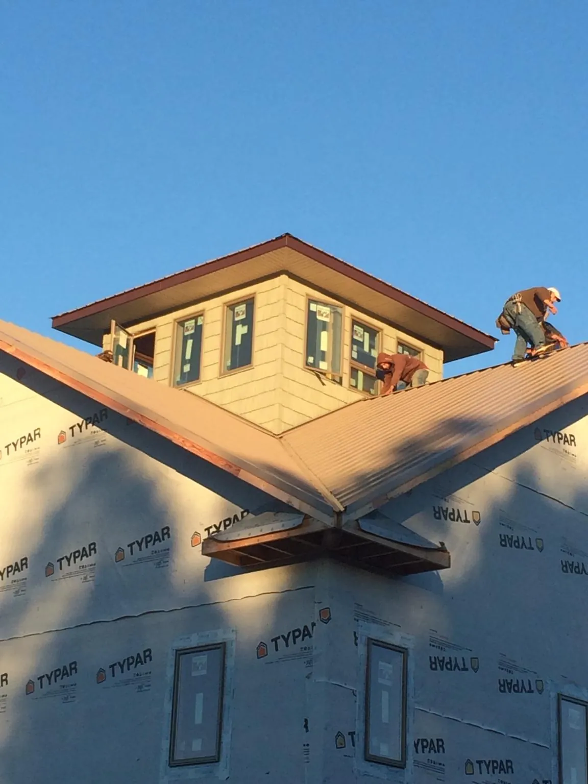 Roofers working around a rooftop cupola on a new metal roof at sunset — Roof Waterproofing in Fox River Grove by Roofing Brothers